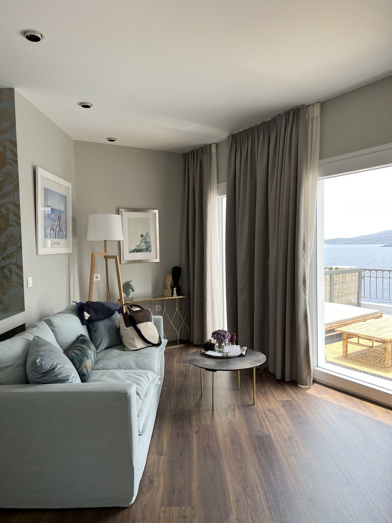 A sitting room opening through a glass door to a balcony and the sea