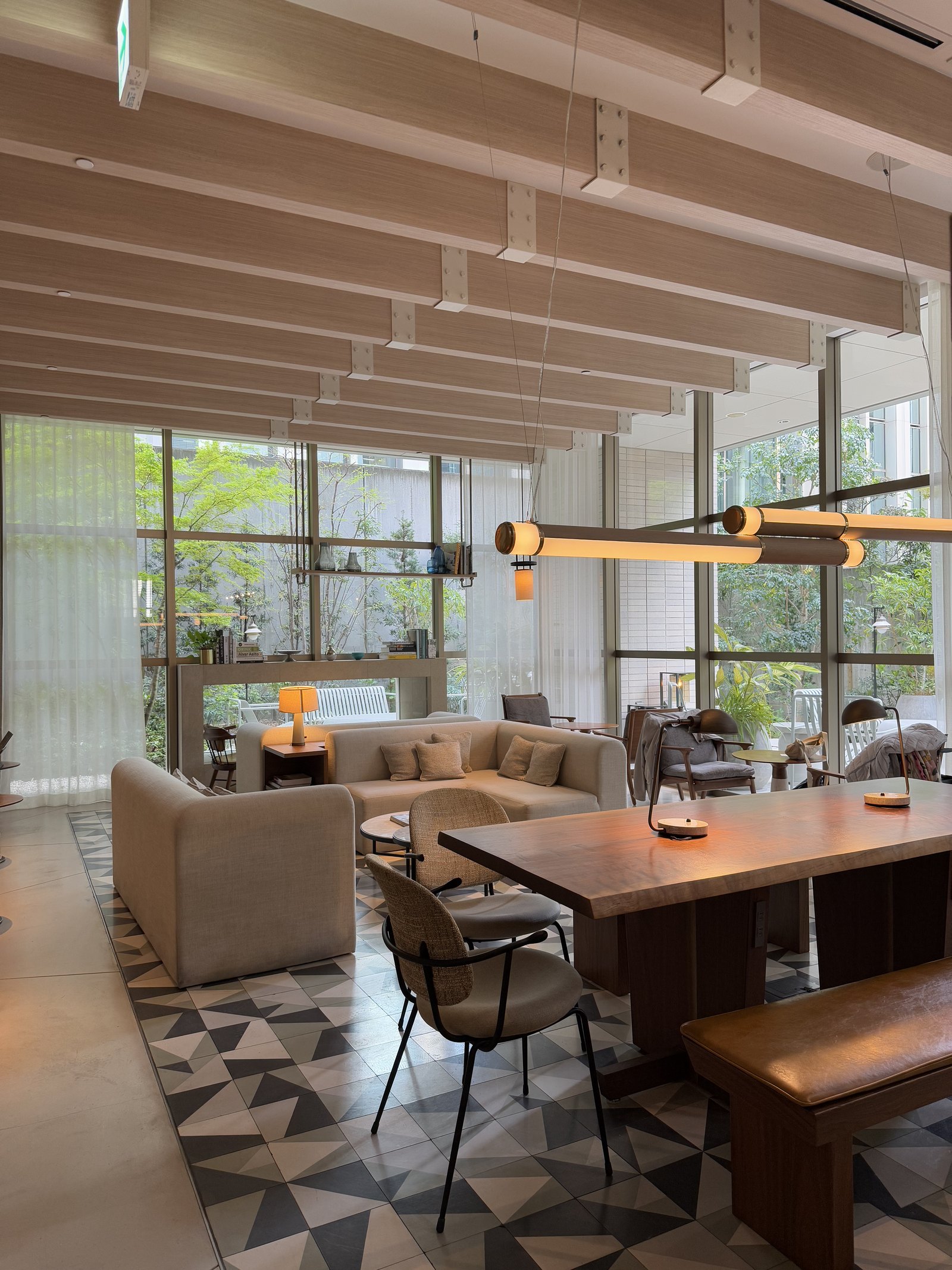 A hotel lounge with a long timber table and low sofas on a black and white triangle patterned floor
