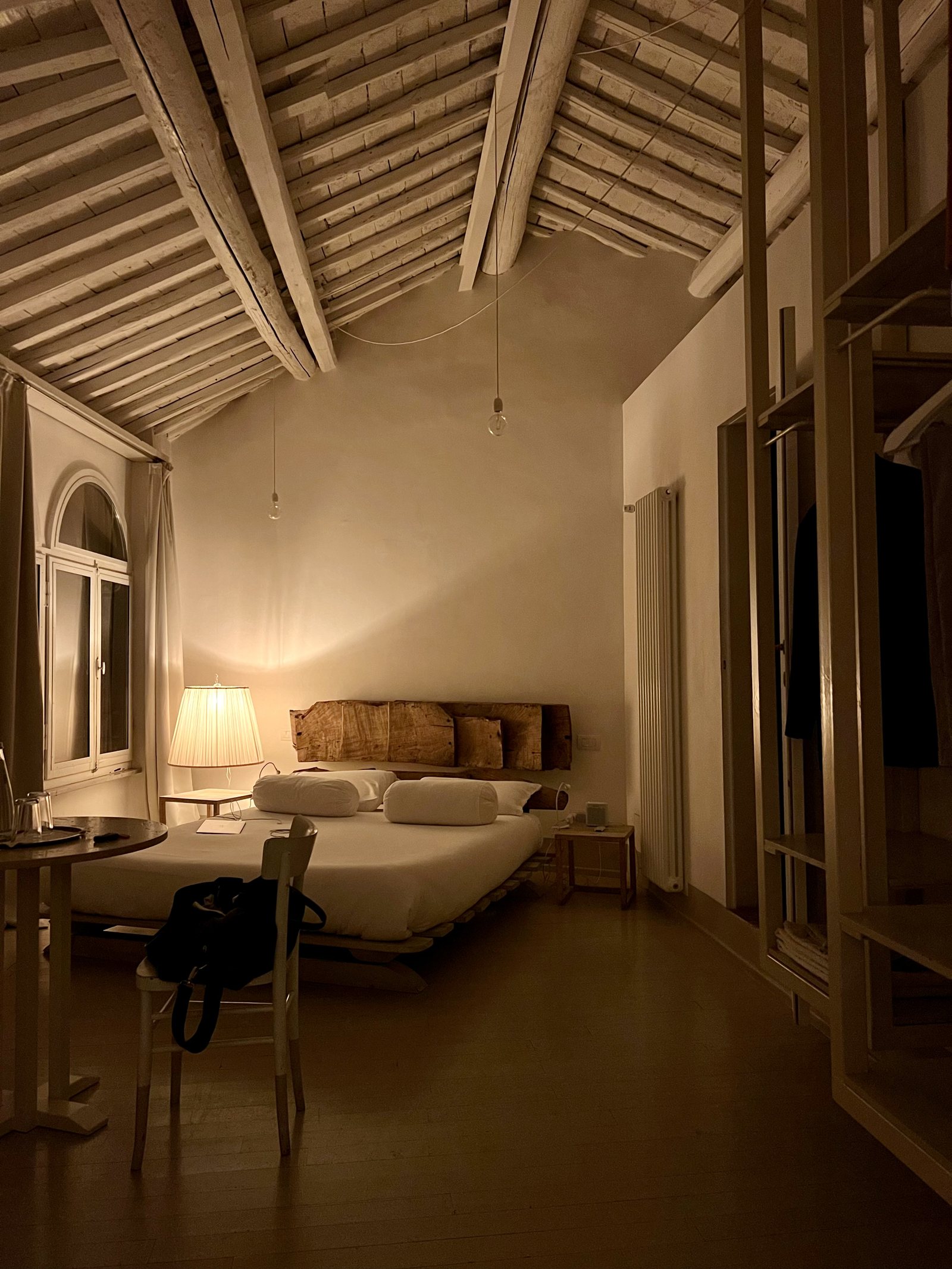 A bed set low in a tall room under exposed rafters