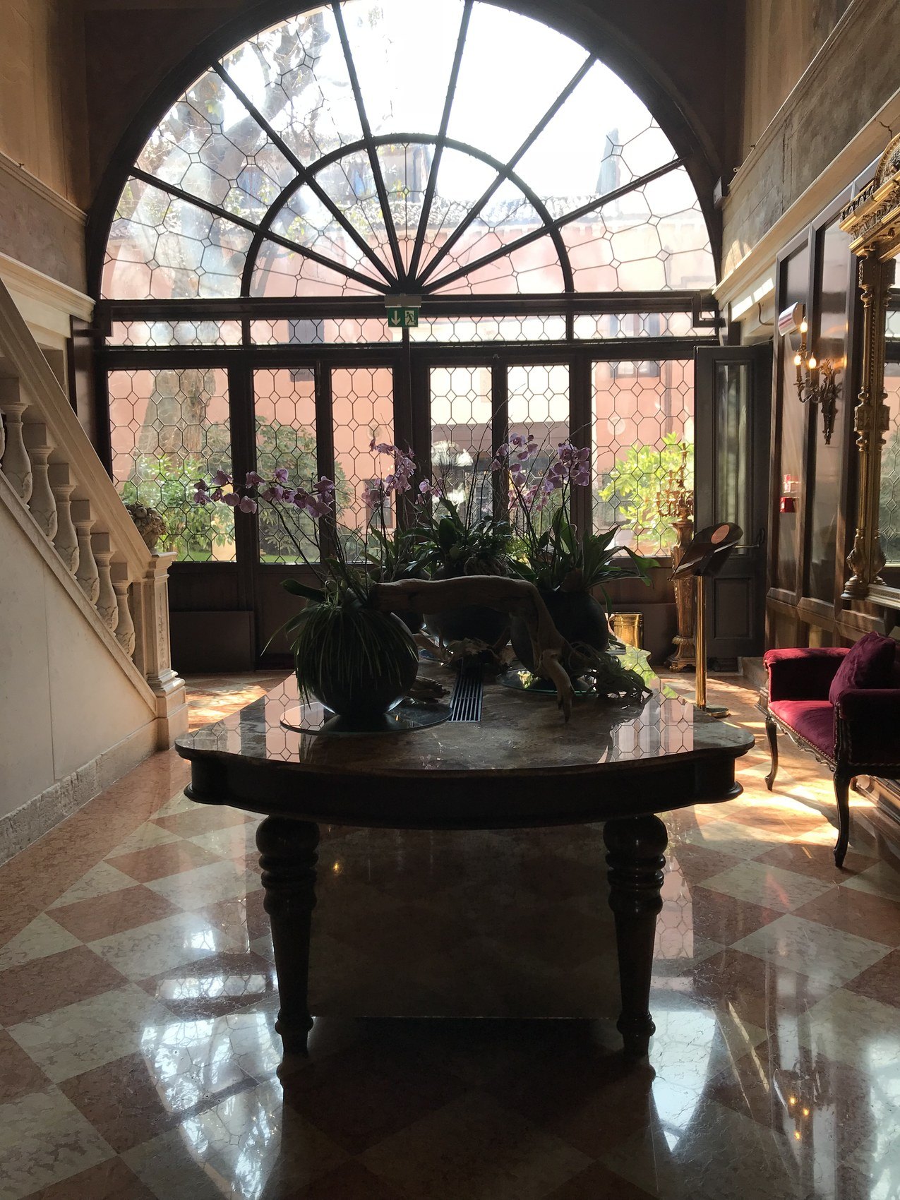 A great arched leaded window over a dark oval table and a marble terrazzo floor