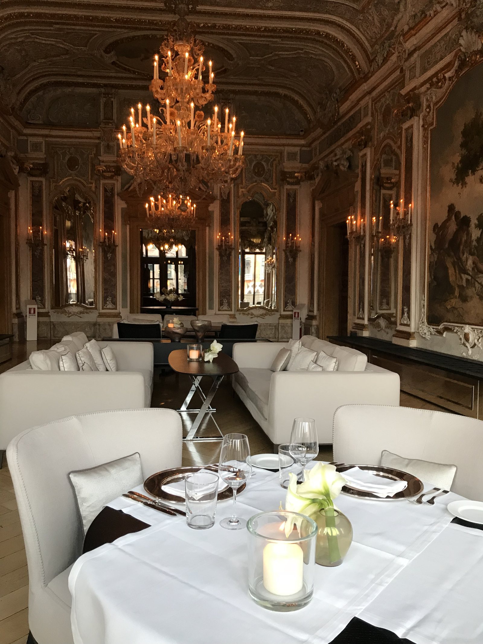 The piano nobile at Aman Venice, laid for dinner under the Murano chandeliers